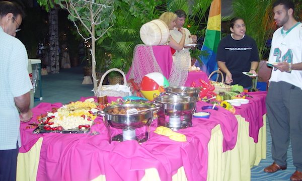 A buffet table draped in hot pink and yellow with chafing dishes and serving pieces