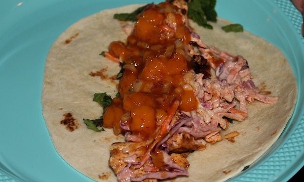 An aqua plate with a tortilla topped with flaked salmon and mango relish.