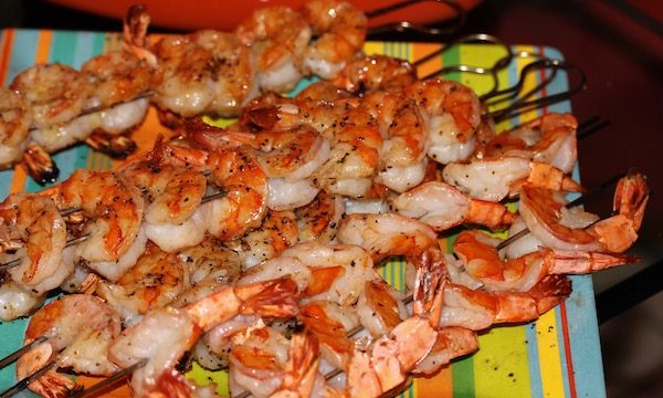 Colorful striped plate topped with skewers of grilled shrimp
