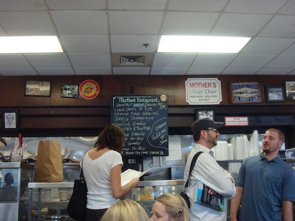 Crowded restaurant with a chalkboard menu on the brown paneled wall