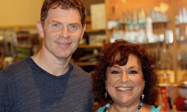 Red haired man in gray t-shirt with arm around dark haired woman in turquoise top
