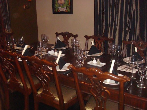 A small dining room with a Mahogany dining room table and chairs, The table is set for a wine dinner.