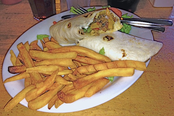 A large white oval plate topped with golden fries and a meat and cheese taco cut in half.