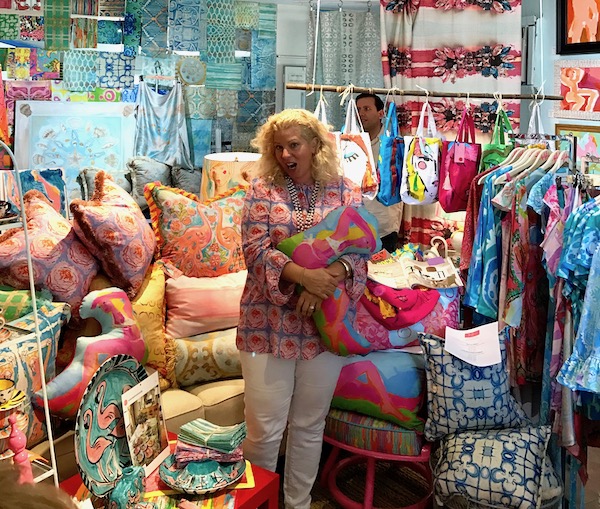 A blond woman talking amidst piles of colorful pillows