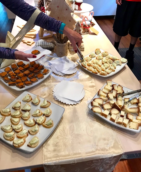 A light wood table with several white rectangular platters of cookies