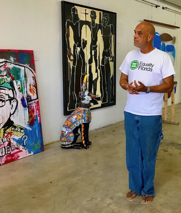 A tall man in flip flops standing in an art gallery