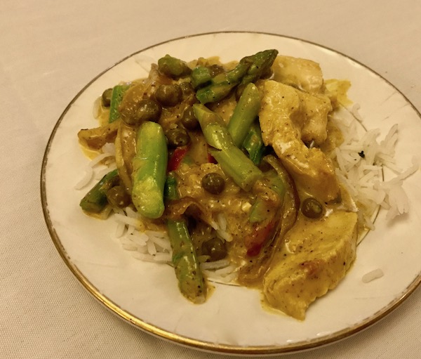 Chicken curry and asparagus on a white plate with gold edge