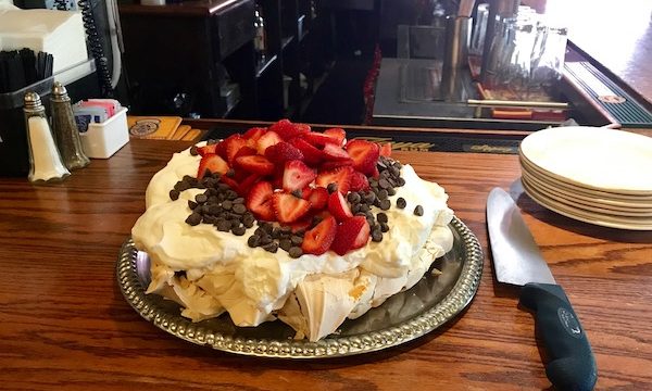 A whole strawberry pavlova pie on a restaurant bar