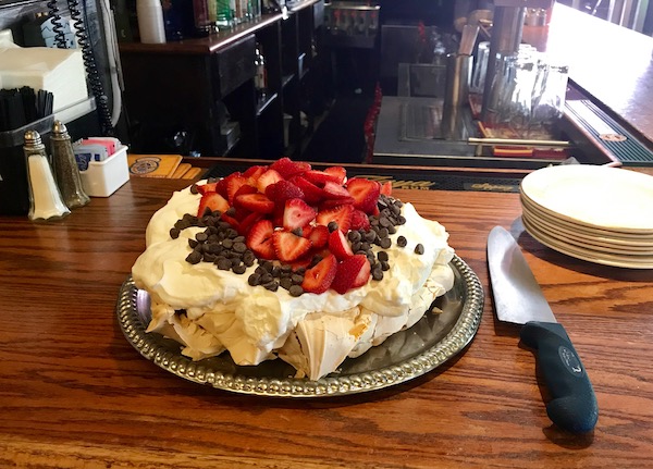 A whole strawberry pavlova pie on a restaurant bar