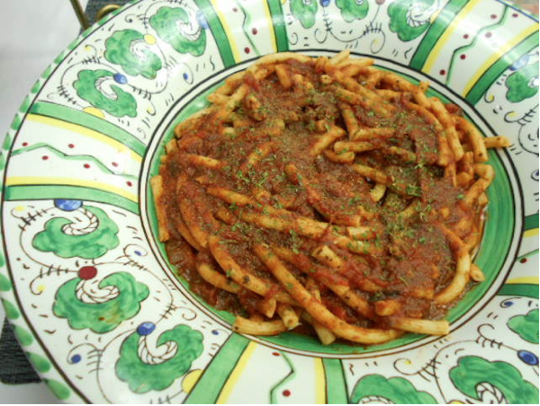 Bucatini pasta with red sauce in a bowl with a green and white rim