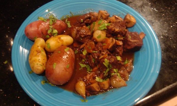 Peacock blue dinner plate with boiled fingerling and red skinned potatoes, wine braised beef, mushrooms and pearl onions