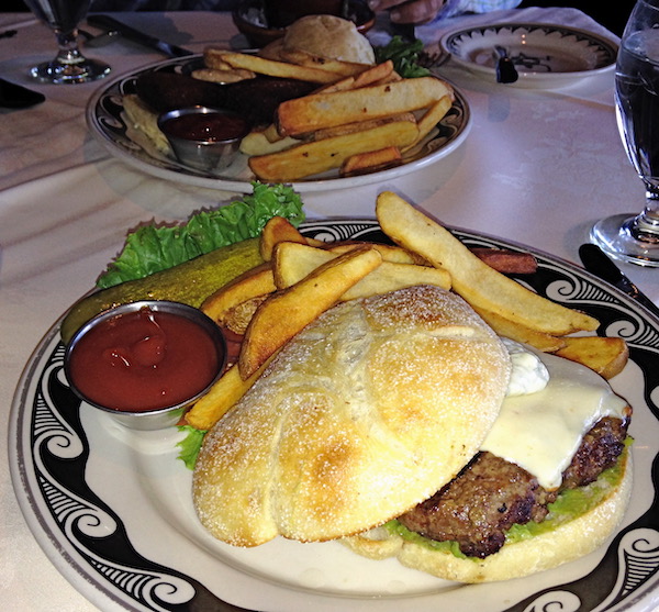 A plate with a swirly black rim holding a burger, fries and a dish of ketchup.