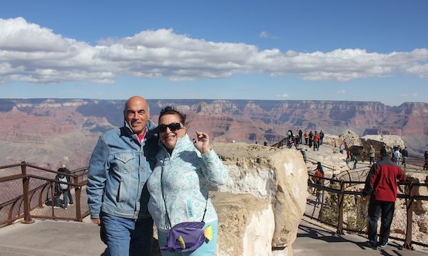 A man with his arm around a woman with the Grand Canyon behind them.