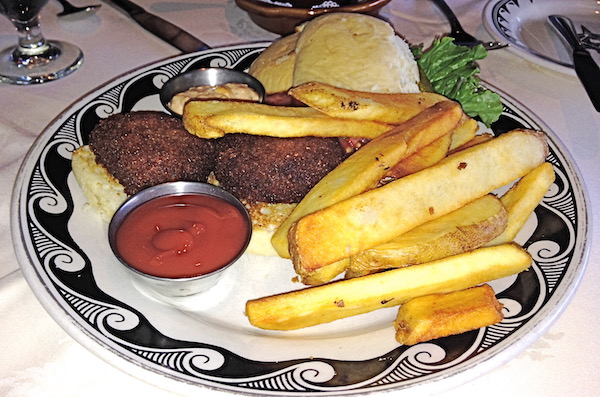 A plate with a swirly black rim that's topped with two crab cake sliders, fries and ketchup.