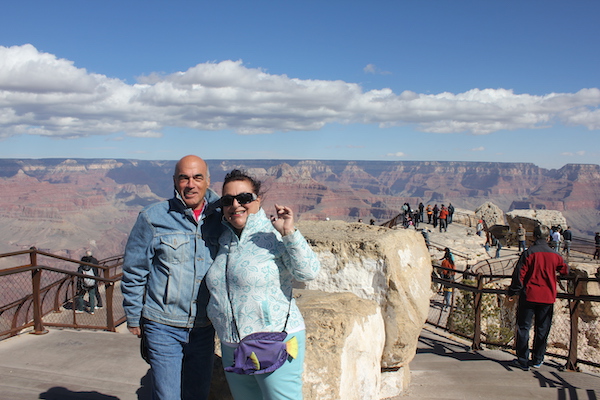 A man with his arm around a woman with the Grand Canyon behind them.