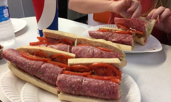 Capicola, Genoa Salami and Provolone Sub cut in half on a white paper plate