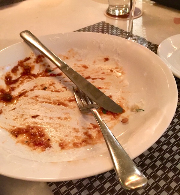 A white plate with the tiniest remains of red sauce