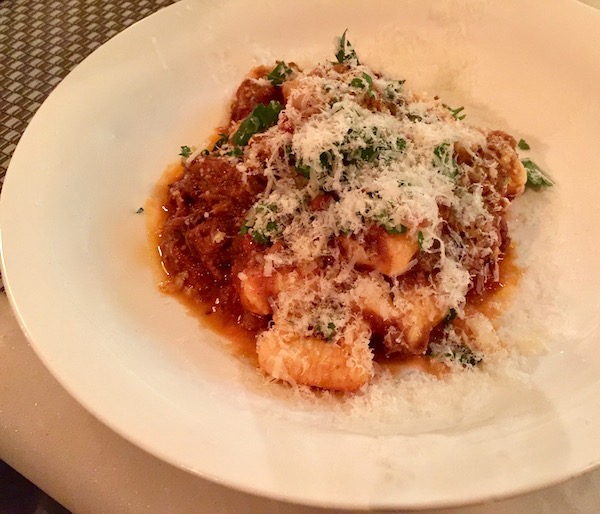 A large white dish with gnocchi and red sauce topped with grated cheese and parsley