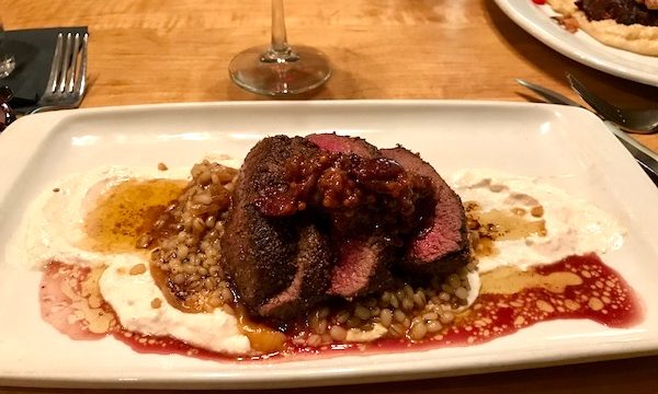 Venison with Caramelized Onion, Horseradish Creme Fraîche and Seasonal Jam on a white rectangular plate