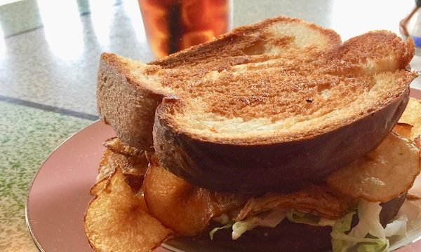 A grilled sandwich with chips inside on a pink plate