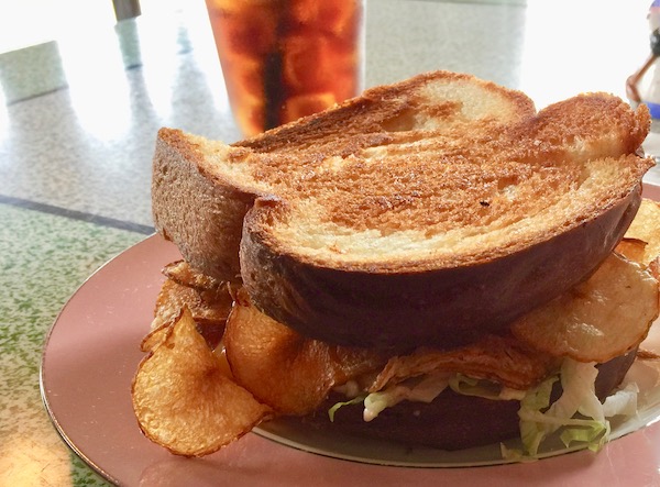 A grilled sandwich with chips inside on a pink plate