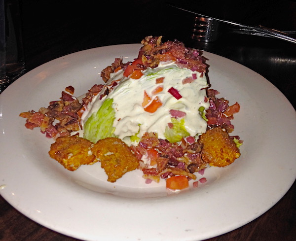 A white plate topped with Wedge Salad with Blue Cheese Croutons and Bacon