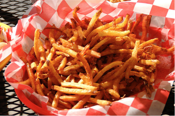A huge pile of fries on red and white checked deli paper