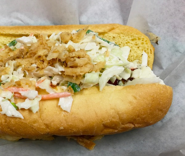 Pictured is half of a hotdog in a bun with coleslaw and onion straws