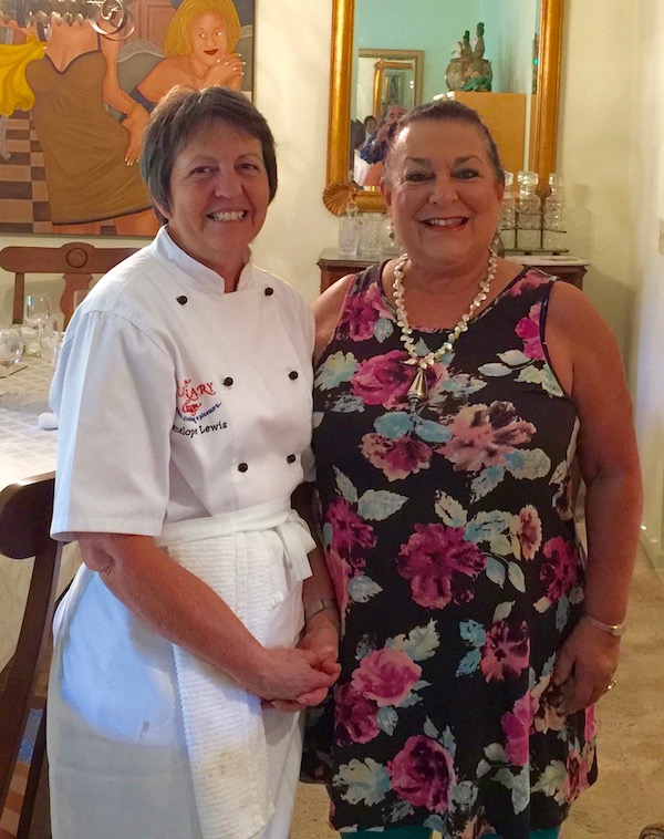 Two women standing beside each other, one in a dress and the other in chef wear.