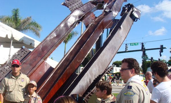A huge piece of mangled steel from the World Trade Center that is surrounded by people