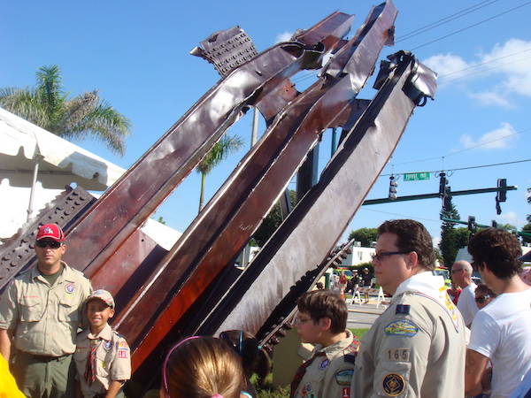 A huge piece of mangled steel from the World Trade Center that is surrounded by people