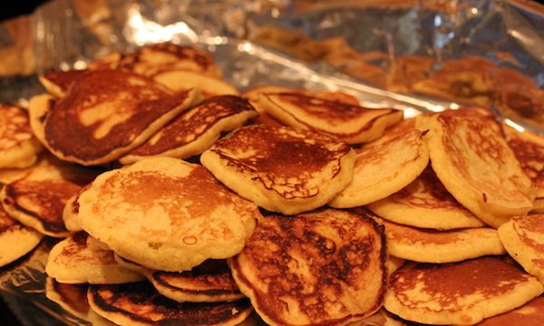 A platter piled high with golden brown small pancakes