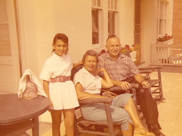 An older man and woman with their young granddaughter sitting outside a house