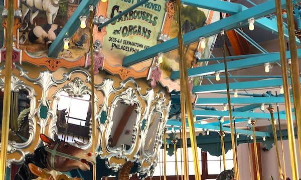 A beautiful antique carrousel in a enclosed building.