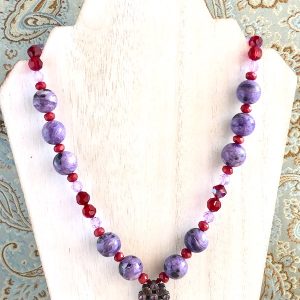Charoite, Ruby Quartz and Swarovski Crystal Necklace on a white washed wood display.