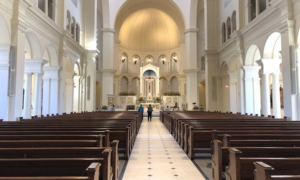 A view of the alter ofHoly Name of Jesus Cathedral in Raleigh NC with pews in the foreground.