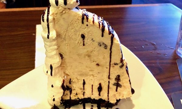 Mile high peanut butter pie drizzled with fudge on a white triangular plate at 12A Buoy Great Casual Dining in Ft. Pierce Florida.