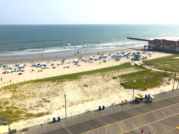 Dunes and white sand beach with blue umbrellas and boardwalk are Fun Things at the Jersey Shore.