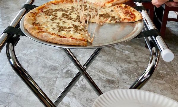 A slice of sausage pizza being lifted from the pizza pan at Jo Jo's Pizza Galloway, New Jersey.