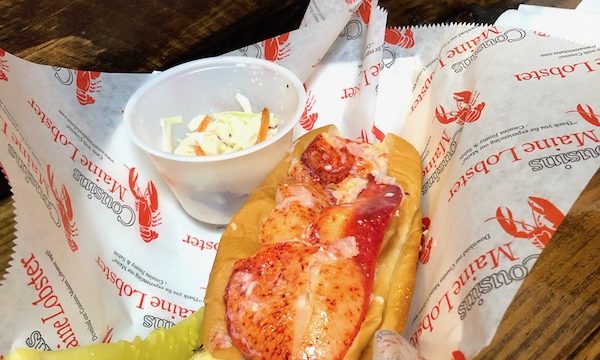 A lobster roll with lemon wedge and pickle spear from Cousins Maine Lobster at the Morgan Street Food Hall.