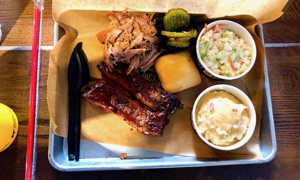 A metal baking pan topped with pulled pork, ribs, coleslaw and baked potato casserole at Dickey's BBQ Pit Cary NC