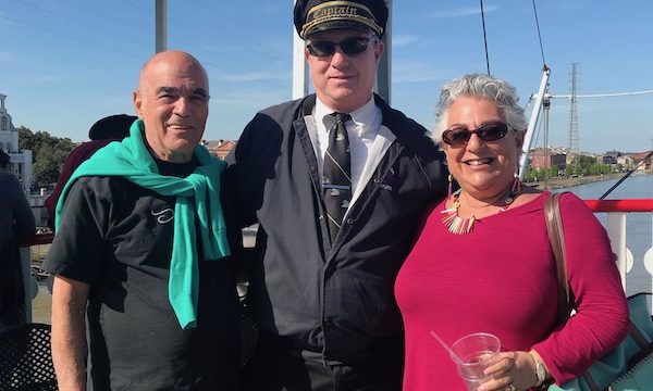 A man and a woman posing with the Captain of our Cruise the Mississippi on the Steamboat Nachez
