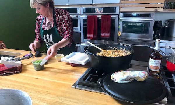 A woman with a container of chopped scallions and a pan of jambalaya at the Southern Food and Beverage Museum
