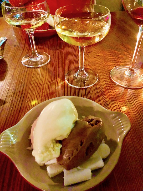 White, brown and pink ice cream in a tan dish with champagne coupes behind at Bywater American Bistro in New Orleans