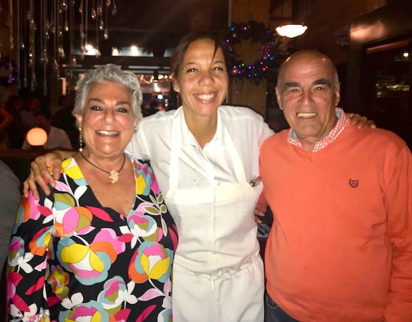 A chef with her arms around a man and a woman at Bywater American Bistro in New Orleans