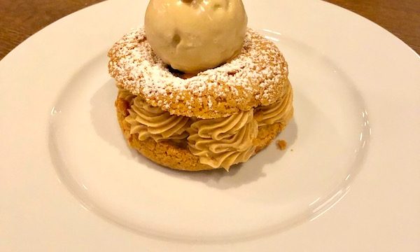 A large cream puff filled with swirls of hazelnut pastry cream and topped with hazelnut ice cream at Couvant Bar and Brasserie in New Orleans