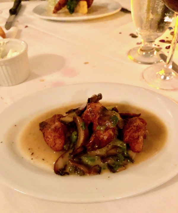 A plate of sweetbreads with potato leek cake, mushrooms, greens and butter sauce with capers at Brigtsen's in New Orleans Revisited