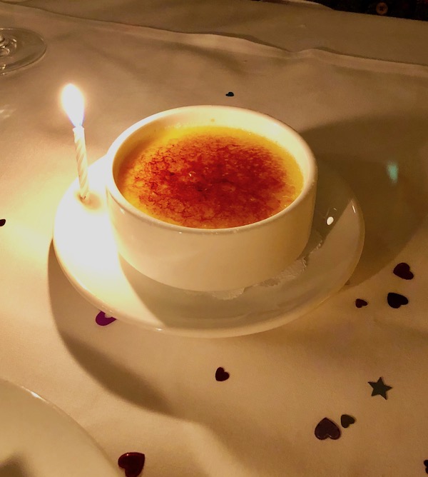 A ramekin filled with burnt sugar coated custard and a lit candle at Brigtsen's in New Orleans Revisited