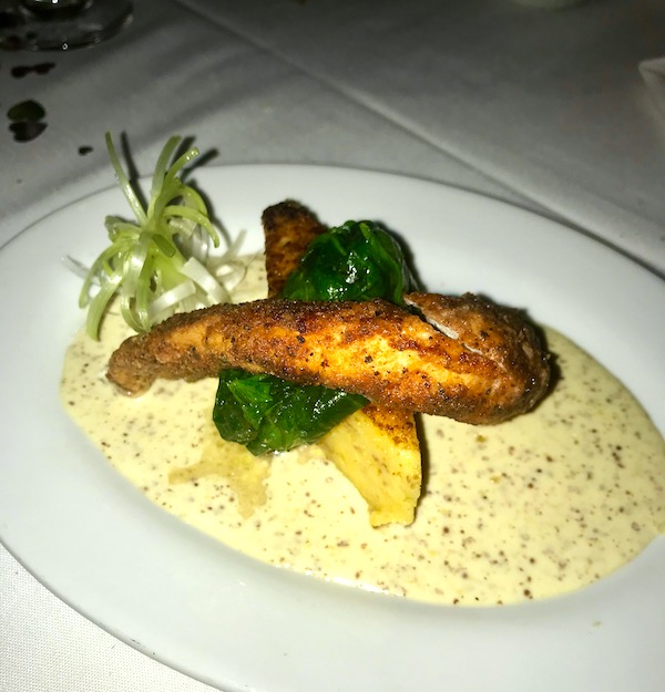 An oval platter topped with rabbit tenderloin, spinach, creamy mustard sauce and a scallion flower at Brigtsen's in New Orleans Revisited