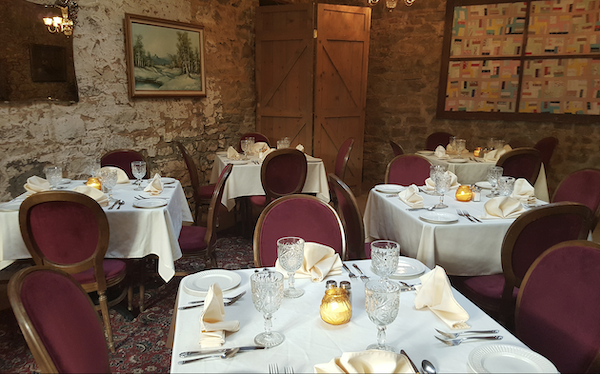 A restaurant dining room with red dark red chairs and white linen from 60 Years of Camel and Ostrich Racing!